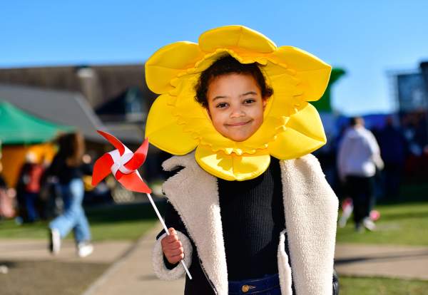 A child wearing a daffodil head dress, holding a windmill.