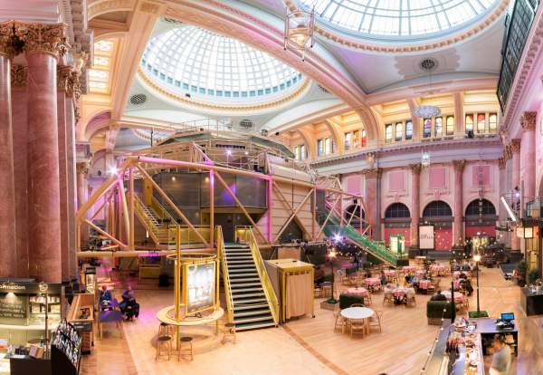 Inside the Royal Exchange Theatre with theatre space in the centre of the room and chairs and tavles set up outside
