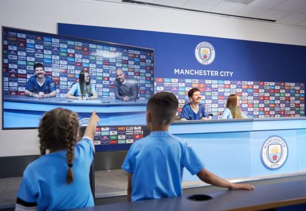 People sat in the press confeerence room on the Manchester City Stadium Tour