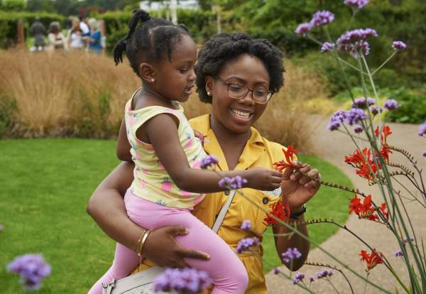 A woman holding a child looking at plants