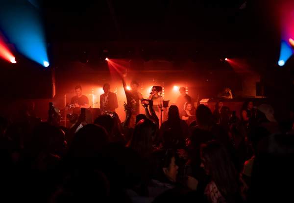 Band lit up on stage with a crowd watching