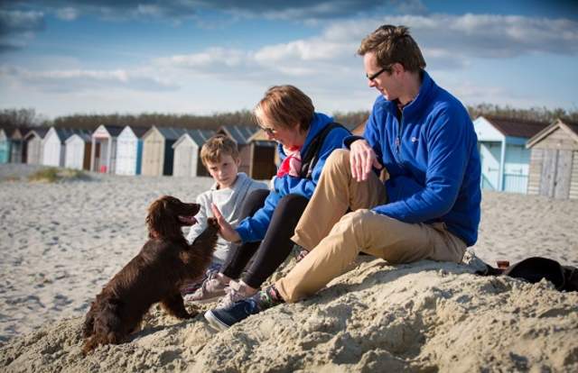 Family sitting on a sandy beach in West Sussex with their dog