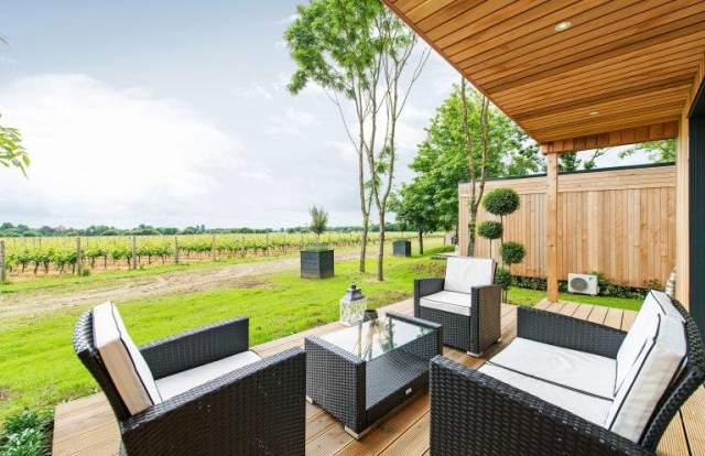 A wooden lodge with a sofa set looking out to the vineyards at Tinwood, Sussex