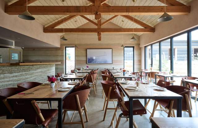 Interior view of wooden tables, chairs and beams in Knepp Wilding kitchen restaurant