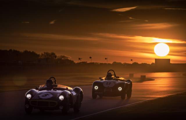 Cars race on the circuit at sunset at Goodwood Revival in Sussex