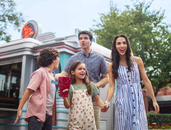 A family walking and sharing popcorn in a theme park.