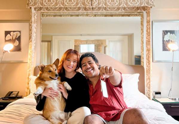 Couple with dog on hotel bed