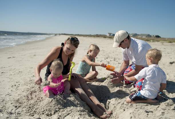 Family building sandcastles on Caswell Beach, NC.