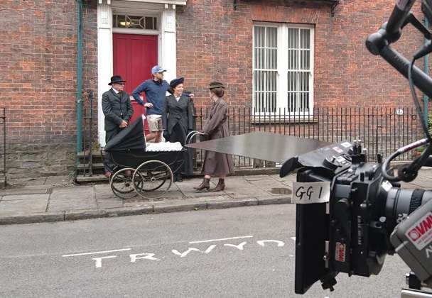 Film set on a street in swansea with cameras and actors standing in a doorway