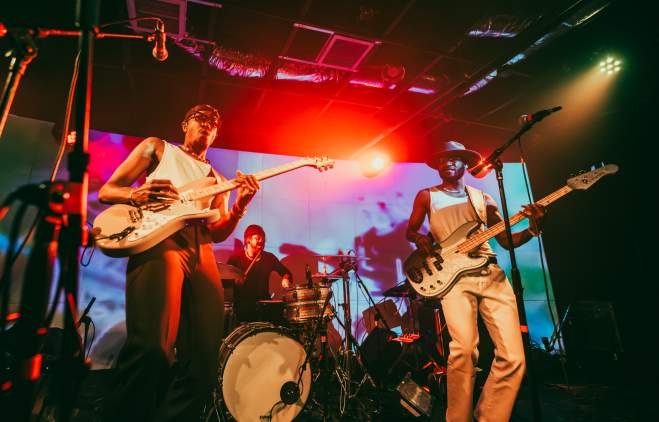 Band on stage with bright, colorful lights shining on them.