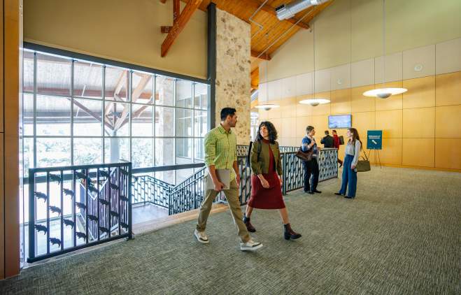 Image of a group of people dressed in business casual walking into the Palmer Events Center and chatting with one another.