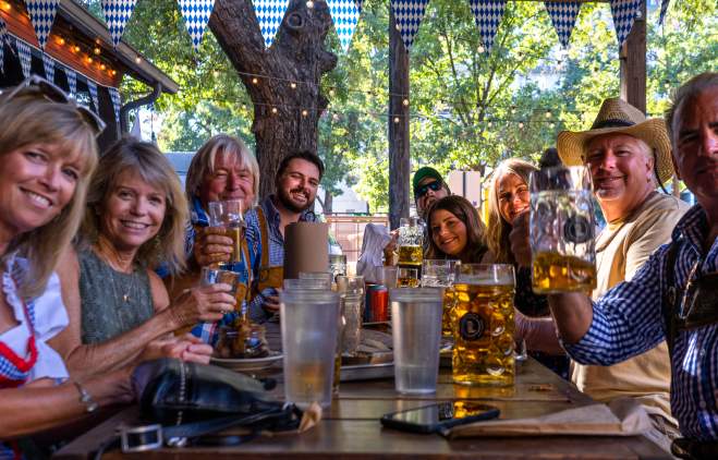 Image of eight people gathered around a table drinking beer.