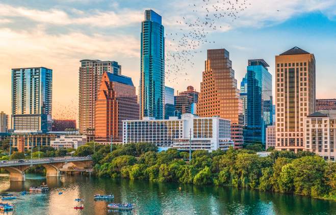 bats flying from the congress bridge in front of Austin skyline at sunset