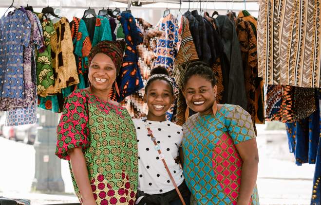 Three women in front of colorful garments at the outdoor Black Makers Market in Austin Texas