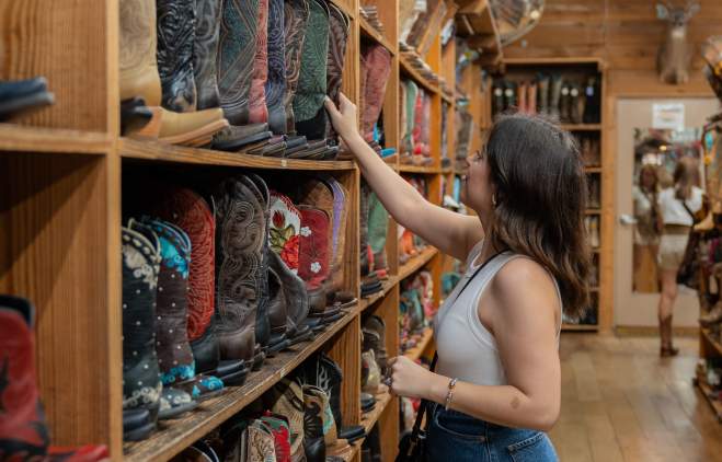 Girl reaching for a pair of cowboy boots at Allens Boots.
