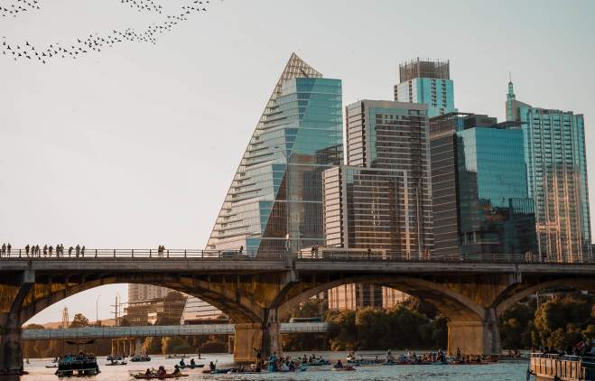 Austin city skyline with birds flying over a bridge at Lady Bird Lake