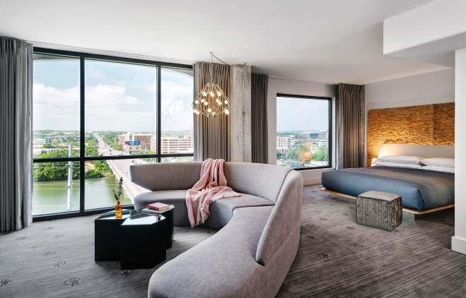Large, modern hotel room with floor to ceiling windows overlooking Congress Avenue Bridge.