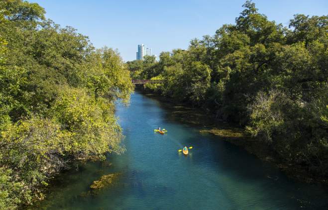 Two kayakers paddling through the Barton Creek Greenbelt in austin texas