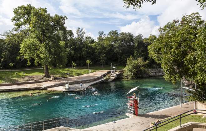People swimming in Barton Springs Pool with lifeguard in stand