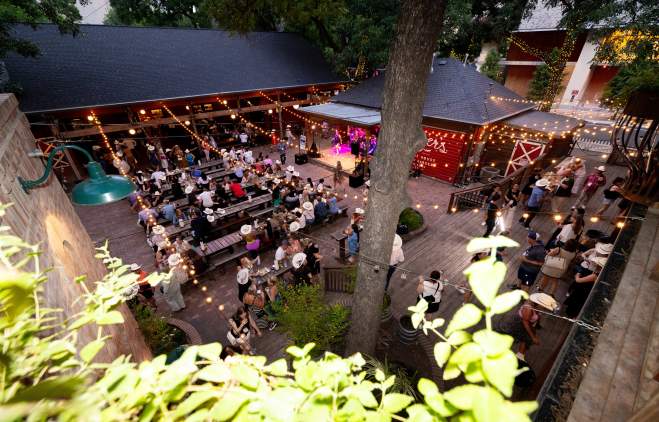 Aerial photo of the CEMA Summit group having an offsite event on the outdoor patio at Banger's with string lights hung over the patio.