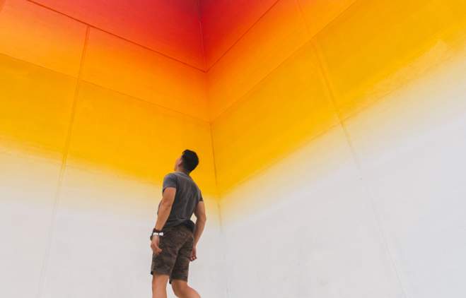 man jumps in front of Tau Ceti rainbow Mural in downtown Austin texas