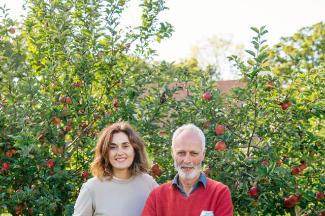 Two owners of Trenchmore Farm in Sussex standing in the cider orchard