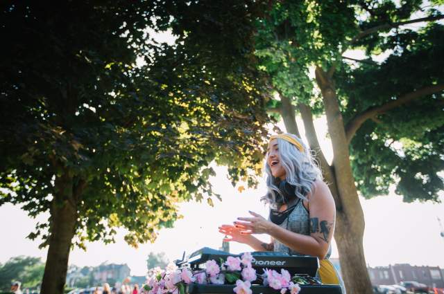 Young girl singing and clapping under trees with sun in background