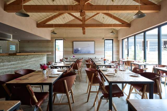 Interior view of wooden tables, chairs and beams in Knepp Wilding kitchen restaurant