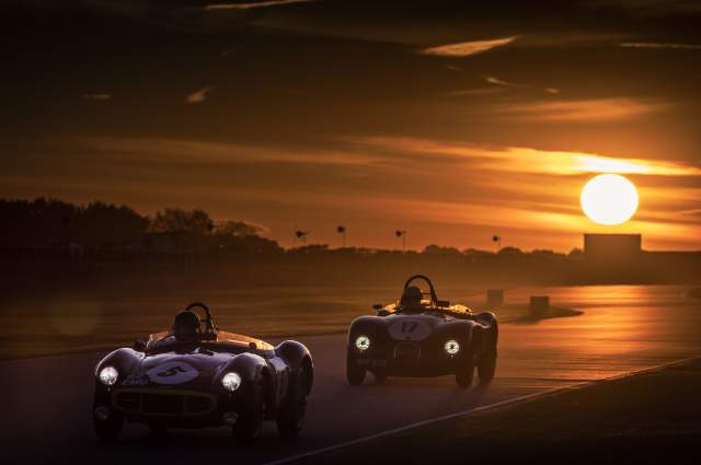 Cars race on the circuit at sunset at Goodwood Revival in Sussex