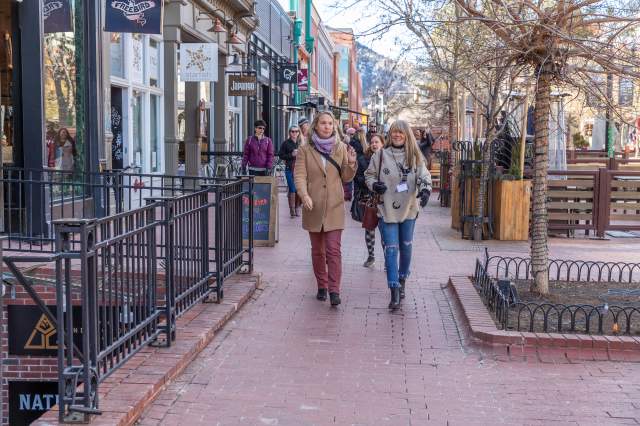 Two women walking along Pearl Street in winter in Boulder wearing conference name tags