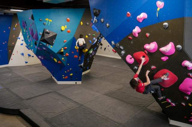 Woman climbing an indoor rock wall at The Spot Gym in Boulder, CO