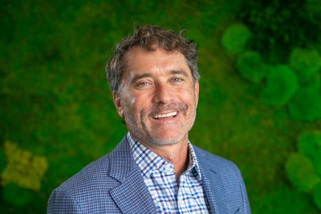 Smiling man wearing a blue sport coat and blue plaid collared shirt