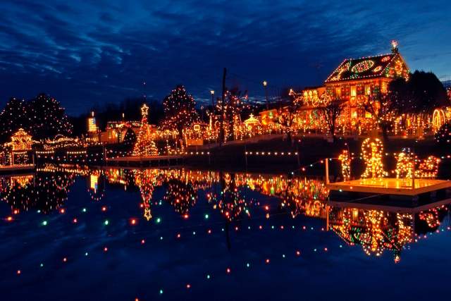 Houses decorated with holiday lights by a pond