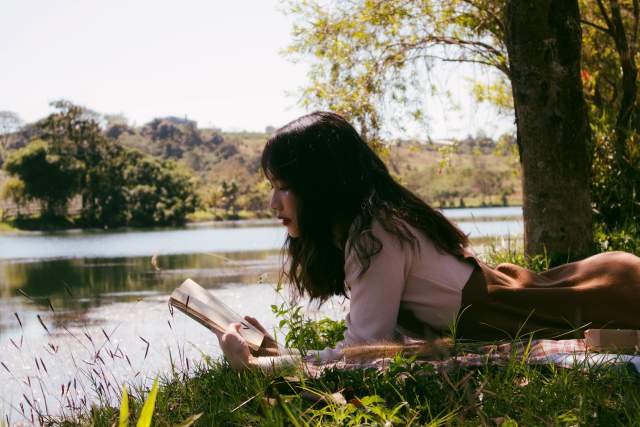 Woman reading near lake
