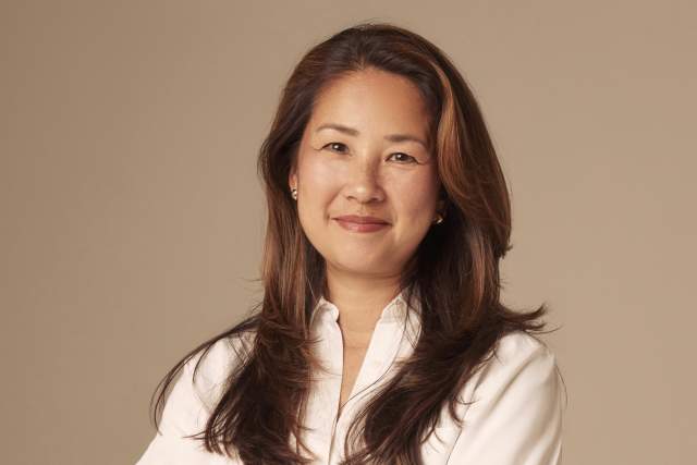 Smiling woman standing with her arms crossed in white button down shirt