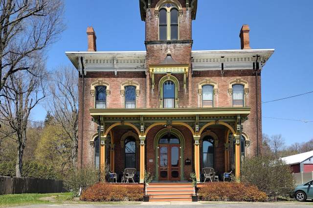 Exterior of a Victorian bed and breakfast with a flower bed with yellow flowers in front