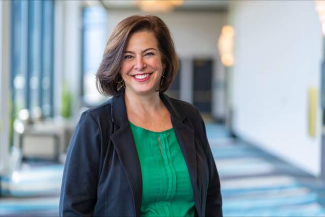 Smiling woman in green shirt and dark blue blazer