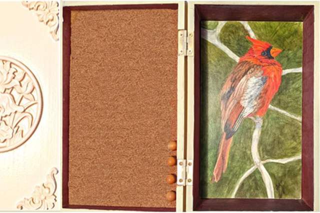 Decorative open box featuring a relief carving of a floral design on the left and a painted image of a cardinal on a branch on the right.