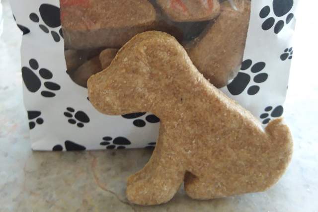 Transparent bag of Tailwaggin Temptations Peanut Butter Pups dog treats, shaped like dogs, decorated with a black and white paw print design.