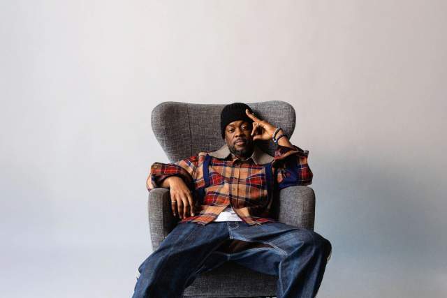 Man wearing a plaid shirt, jeans, and boots relaxed in a comfortable chair