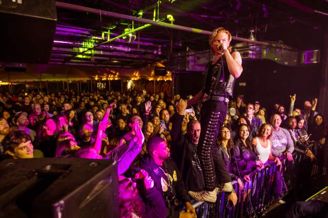 Musician standing on barricades with a full crowd below him.