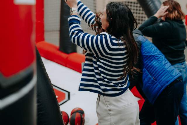Two women playing a basketball freethrow game on a blow up basketball game branded with University of Utah