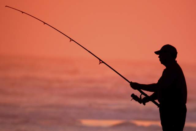 A silhouette of a man fishing.