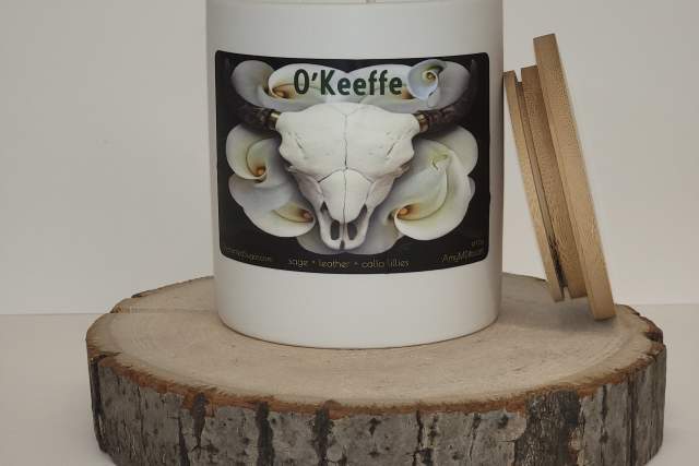 A candle labeled "O'Keefe" containing mushrooms, mounted on a sliced log attached to a white wall.