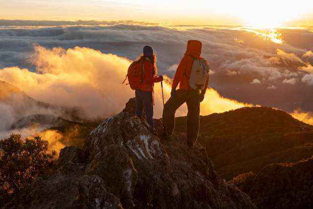 Hikers watching the sunrise from the summit of Volcan Baru, surrounded by clouds and mountainous landscapes in Panamá.