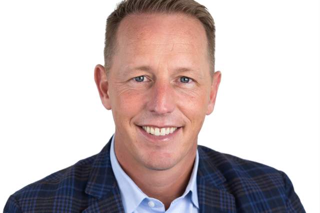 Smiling man in dark blue plaid jacket and light blue button-up shirt