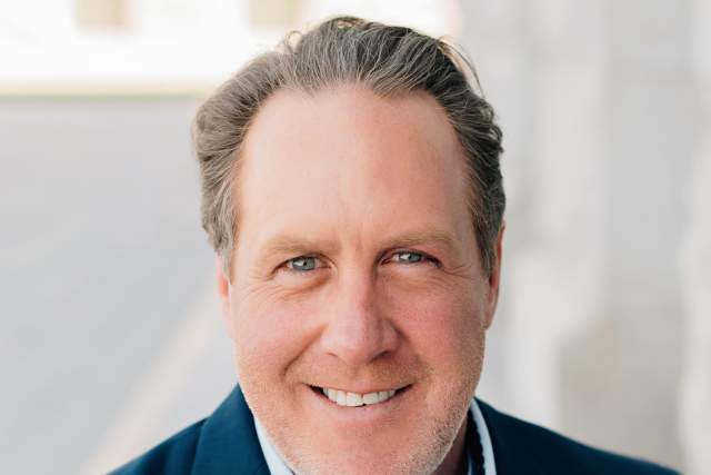 Smiling man in Dark blue blazer and light blue button up shirt