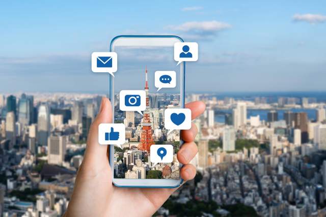 mobile phone with symbols from social media platforms with city in background
