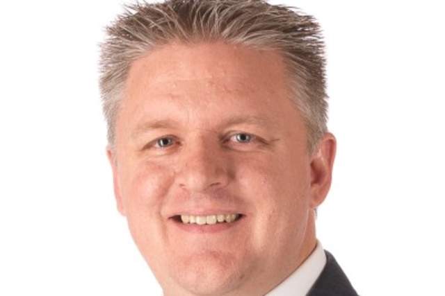 Smiling man in dark grey suit and button down shirt