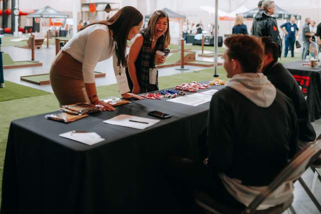 Two women looking at items on a vendor table under a yellow and orange umbrella